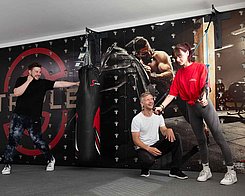 Two athletes pose in front of a Cube Sports wall.